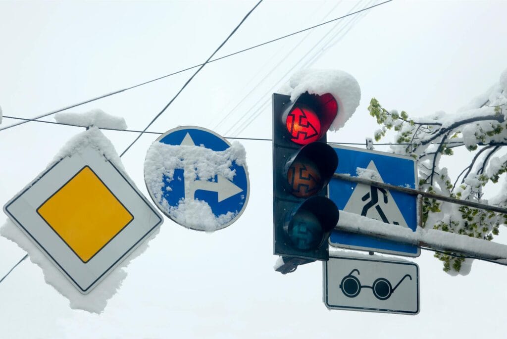 snow covered traffic signs and red light